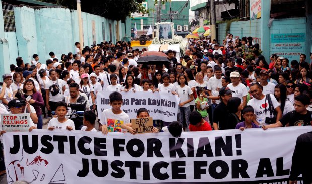 Mourners display a streamer during a funeral march for Kian delos Santos, a 17-year-old student who was shot during anti-drug operations in Caloocan
